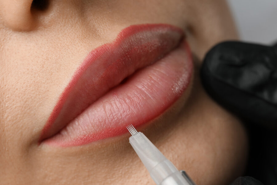 Young woman undergoing procedure of permanent lip makeup in salon, closeup